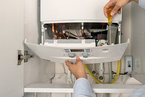 Heating technician repairing a residential boiler in Daly City