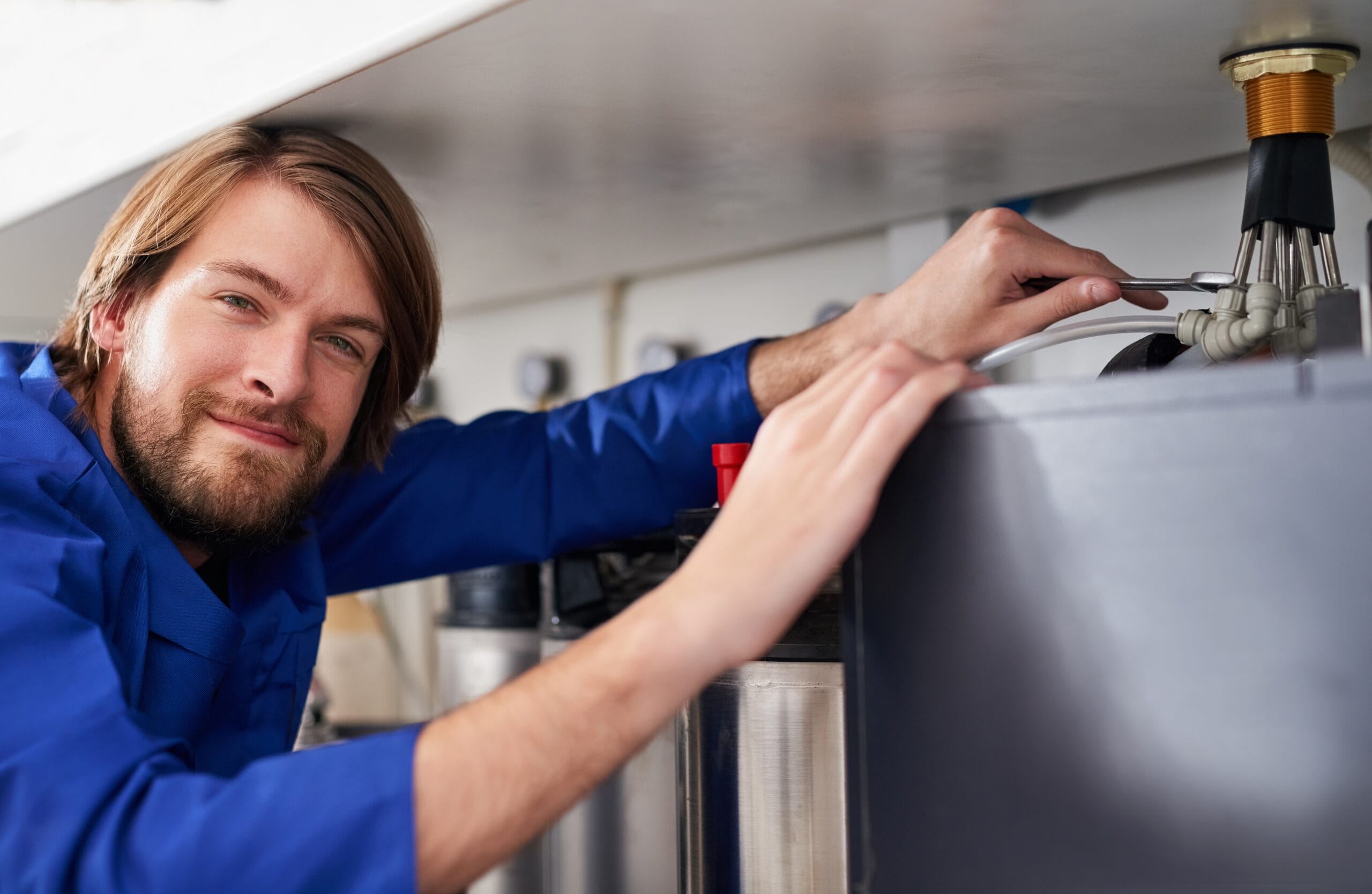 Technician servicing a residential water heater tank in Daly City